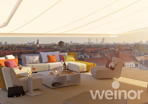 Moderne Dachterrasse mit Markise, stilvollen Loungemöbeln und Stadtblick bei Sonnenuntergang.