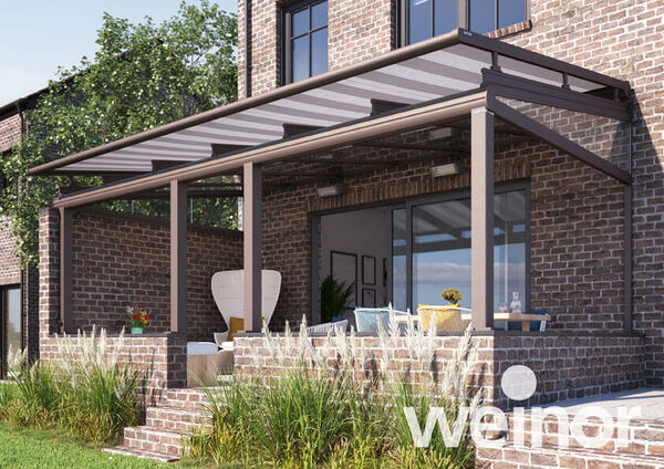 Überdachte Terrasse mit moderner Pergola an einem Backsteinhaus, Gartenmöbel im Freien.